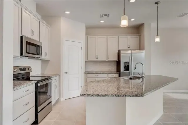 a kitchen with stainless steel appliances granite countertop a sink a stove and a refrigerator