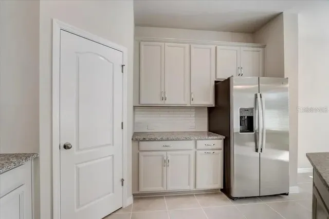 a kitchen with white cabinets and refrigerator