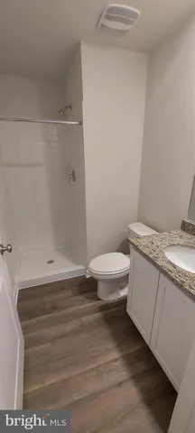 a bathroom with a granite countertop toilet and a shower