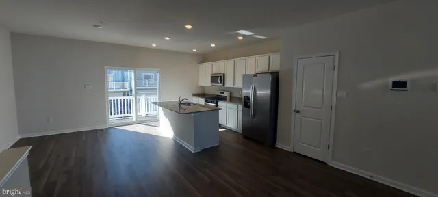 a view of a refrigerator in kitchen and an empty room