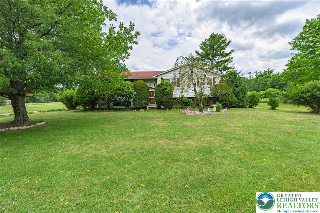 678 Interchange Road Kresgeville, PA 18333 - Photo 41 of 45 A well-maintained lawn stretches before a residence, framed by mature trees and lush shrubs.