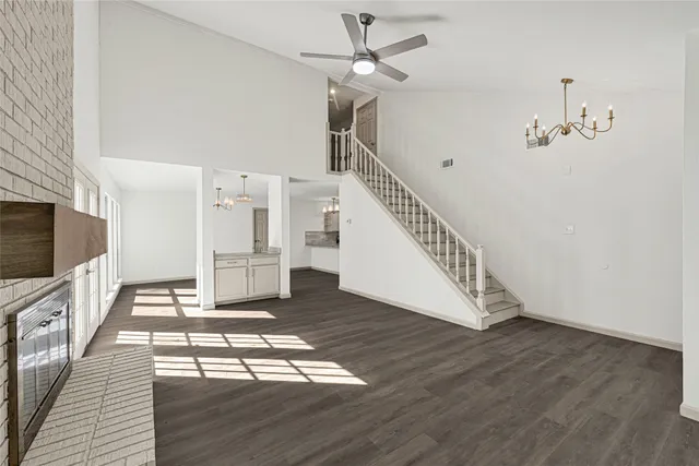 a view of a livingroom with wooden floor a ceiling fan and staircase