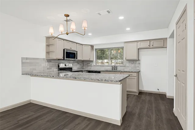 a kitchen with granite countertop a stove and a wooden floors