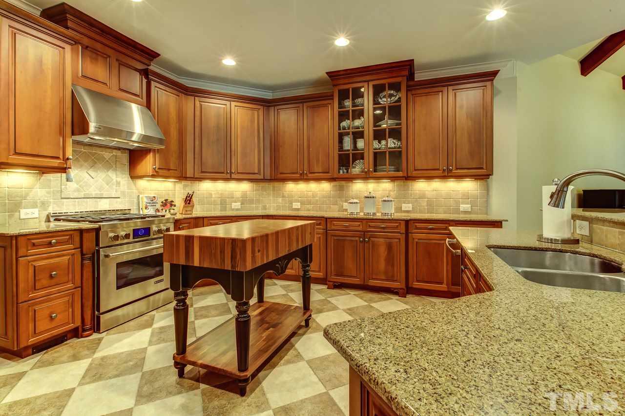 1420 Wynncrest Court Raleigh, NC 27603 - Photo 9 of 30 a kitchen with kitchen island granite countertop a stove a sink and a refrigerator