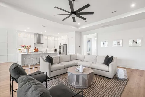 a living room with furniture kitchen view and a chandelier
