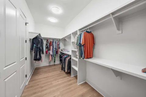 a walk in closet with wooden floor