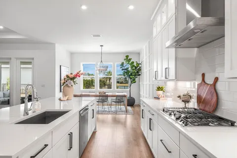 a large white kitchen with stainless steel appliances a stove a sink dishwasher and cabinets with wooden floor