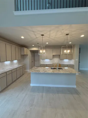a view of a kitchen with kitchen island a sink wooden floor and a counter top space