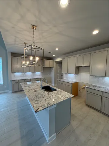 a large kitchen with kitchen island a stove a counter space a sink and a wooden floors