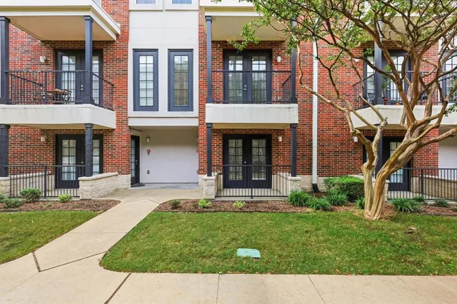 front view of a brick house with a yard and large trees