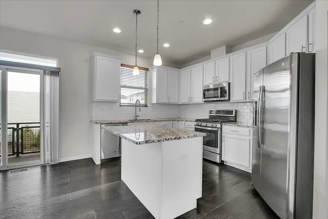 a kitchen with kitchen island a sink stainless steel appliances and window