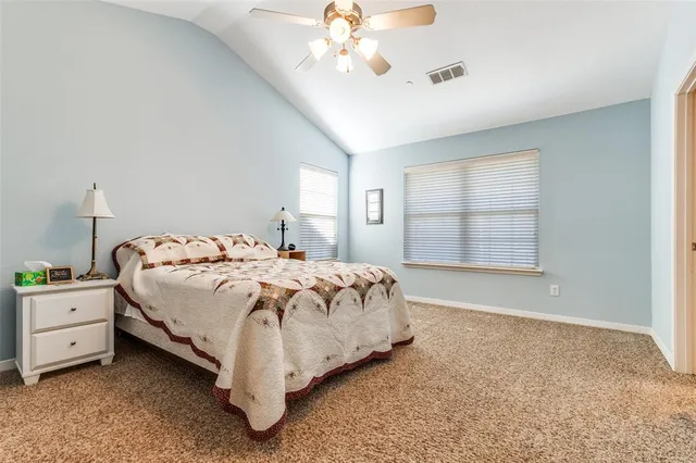 a bed sitting in a spacious bedroom next to a window and a chandelier