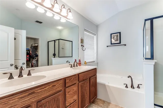 a bathroom with double vanity sinks a large mirror and a bathtub