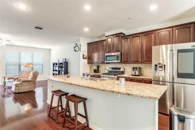 a kitchen with granite countertop wooden cabinets a refrigerator a stove a washer and island