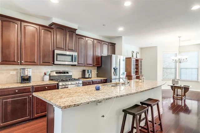 a kitchen with stainless steel appliances granite countertop a kitchen island hardwood floor sink and stove