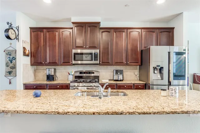a kitchen with stainless steel appliances granite countertop a refrigerator a stove top oven a sink and dishwasher