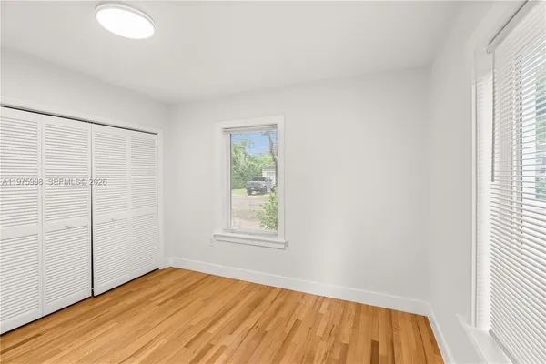 an empty room with wooden floor and windows