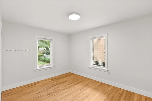 a view of an empty room with wooden floor and a window