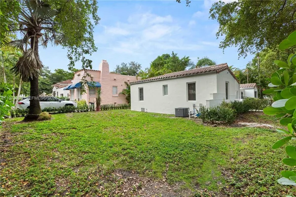 a view of a backyard with plants and large trees