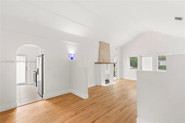 a view of a livingroom with wooden floor and a refrigerator