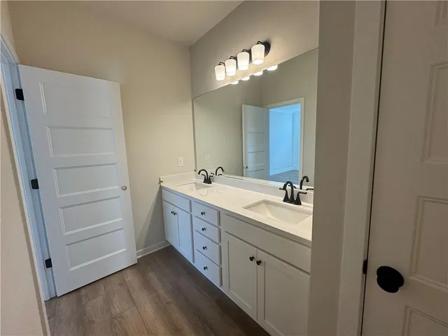 a spacious bathroom with a double vanity sink a large mirror and shower