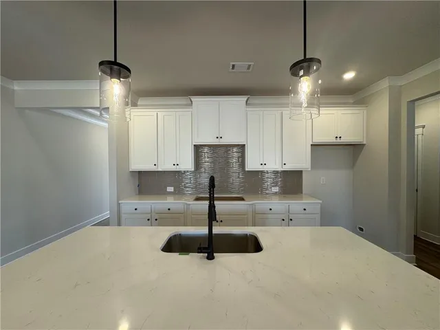 a kitchen with kitchen island a sink a stove and cabinets