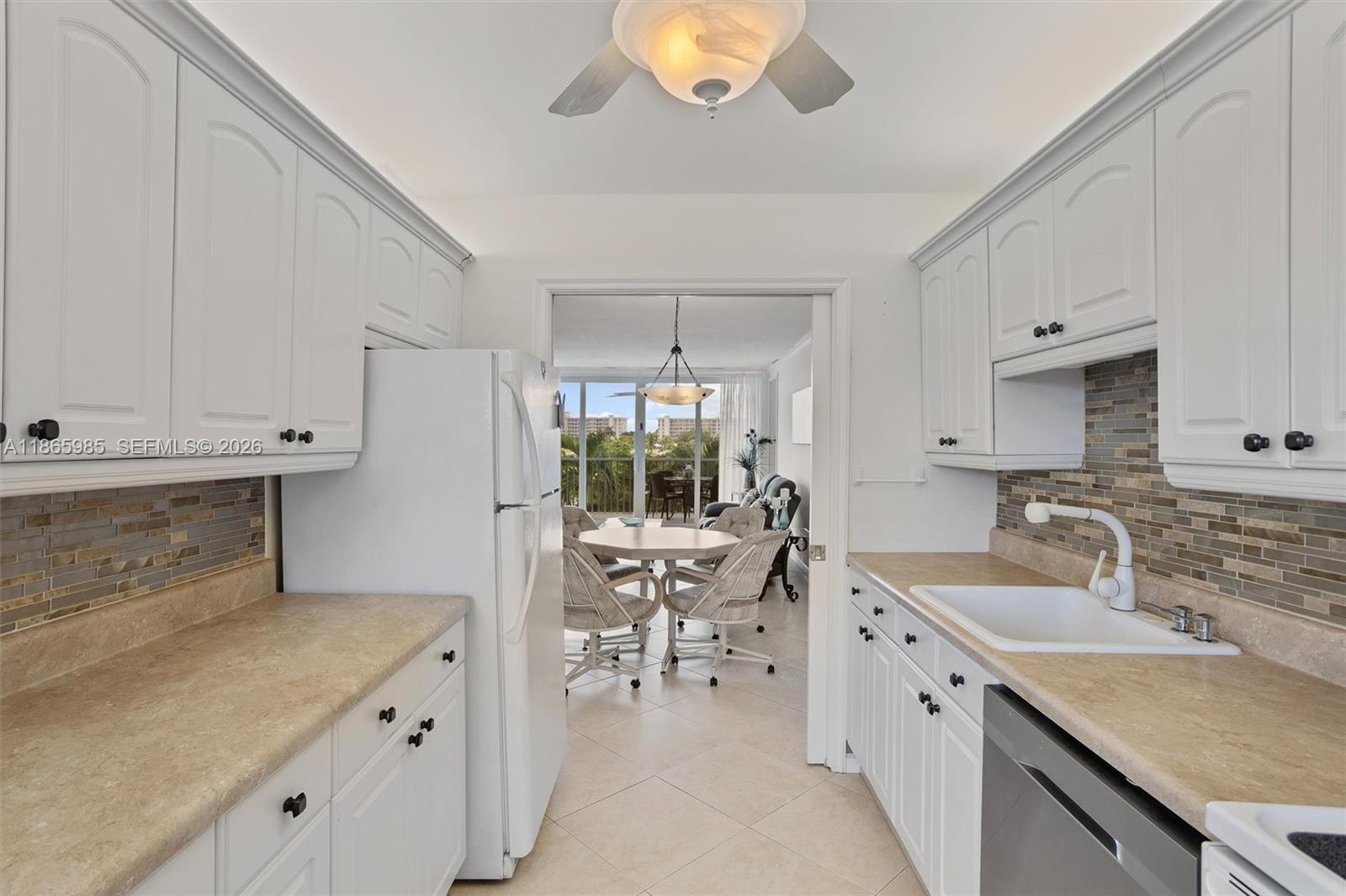 3150 North Course Lane, Unit 402 Pompano Beach, FL 33069 - Photo 5 of 29 a kitchen with a sink dishwasher and white cabinets with wooden floor