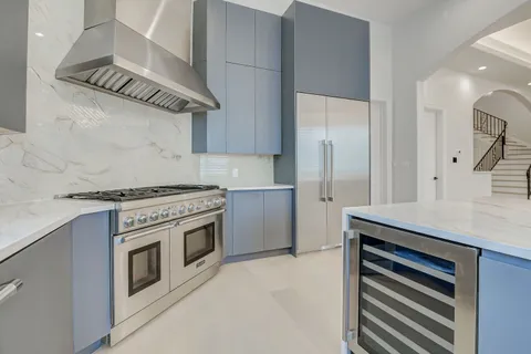 a large white kitchen with stainless steel appliances granite countertop a large counter top and a stove