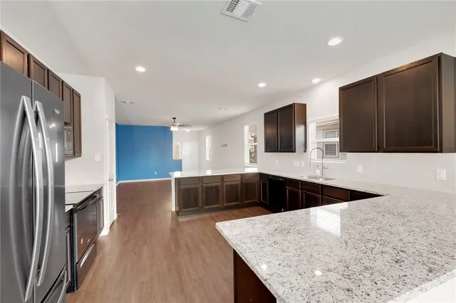 a kitchen with stainless steel appliances granite countertop a sink a stove and a refrigerator