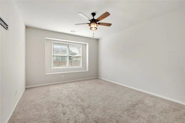 an empty room with window and ceiling fan