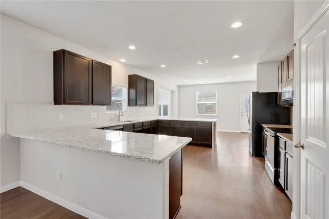 a large kitchen with stainless steel appliances a large counter top a stove a sink a refrigerator and a sink