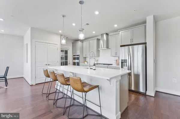 a kitchen with stainless steel appliances kitchen island a table chairs refrigerator sink and microwave