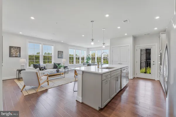 a large white kitchen with lots of counter space a sink and stainless steel appliances