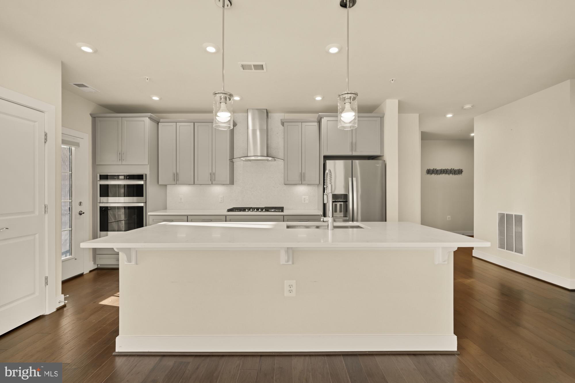 2320 Field Point Road, Unit 4304 Herndon, VA 20171 - Photo 7 of 43 a large kitchen with kitchen island a stove a sink a refrigerator and white cabinets with wooden floor
