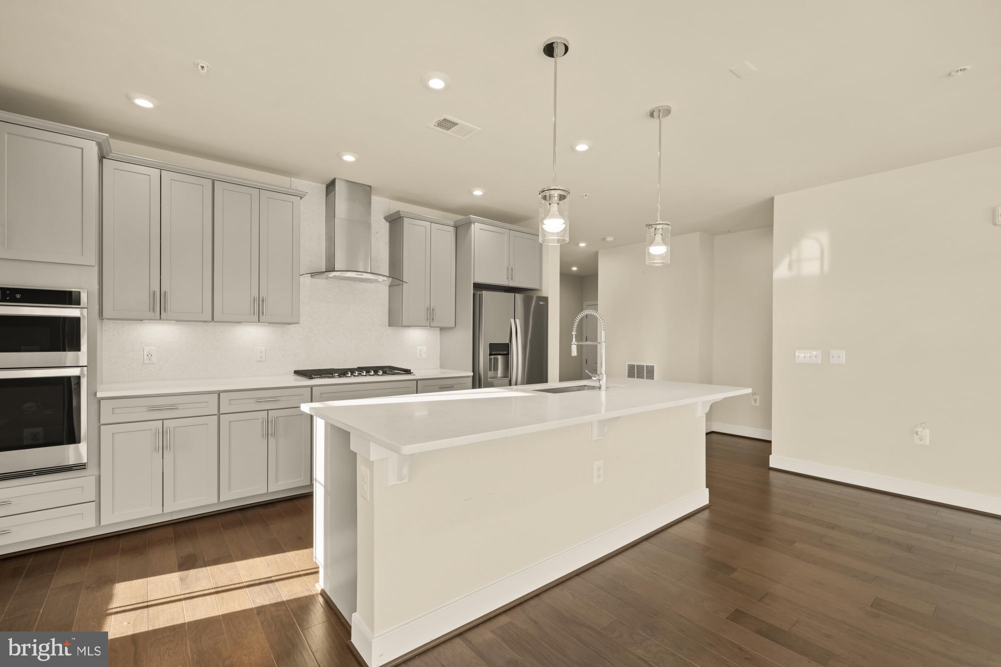 2320 Field Point Road, Unit 4304 Herndon, VA 20171 - Photo 8 of 43 a large white kitchen with a stove a sink a refrigerator and white cabinets with wooden floor