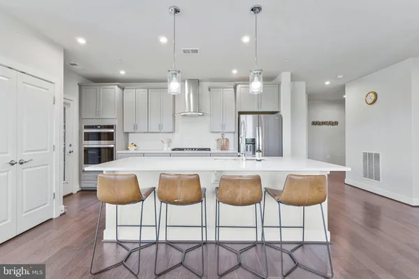 a kitchen with stainless steel appliances granite countertop a kitchen island a stove a cabinets and a chairs