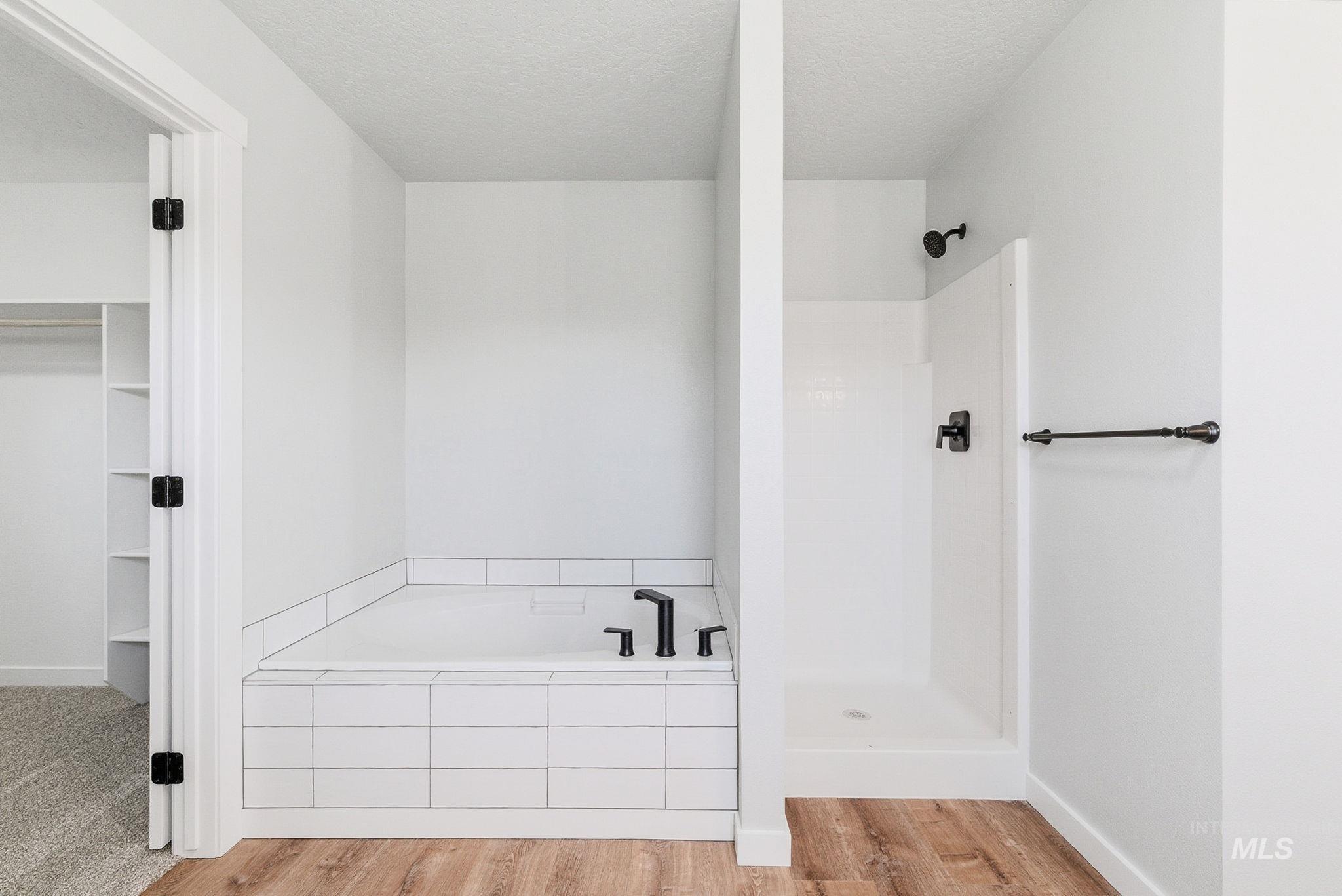 3312 Vistapark Drive Caldwell, ID 83605 - Photo 12 of 17 Bathroom with a bath, light wood-style floors, a textured ceiling, a walk in shower, and a walk in closet