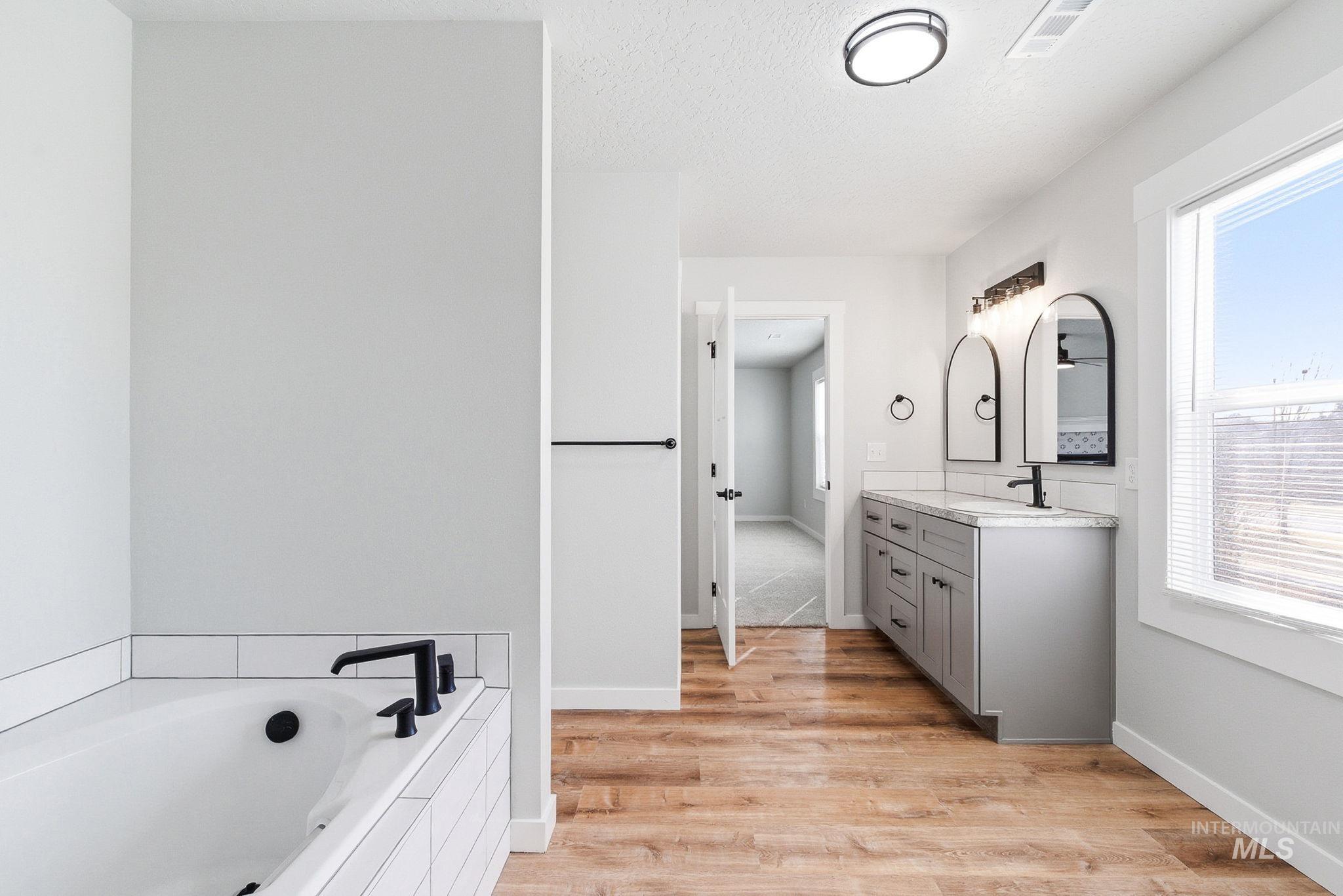 3312 Vistapark Drive Caldwell, ID 83605 - Photo 13 of 17 Full bathroom with vanity, light wood finished floors, a garden tub, and a textured ceiling
