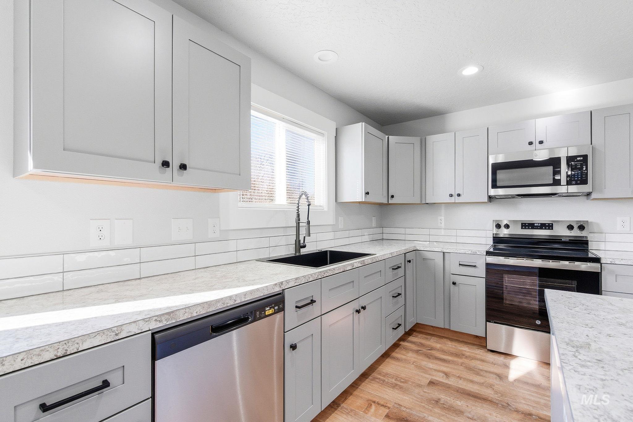 3312 Vistapark Drive Caldwell, ID 83605 - Photo 3 of 17 Kitchen with gray cabinets, stainless steel appliances, light countertops, light wood-style floors, and recessed lighting