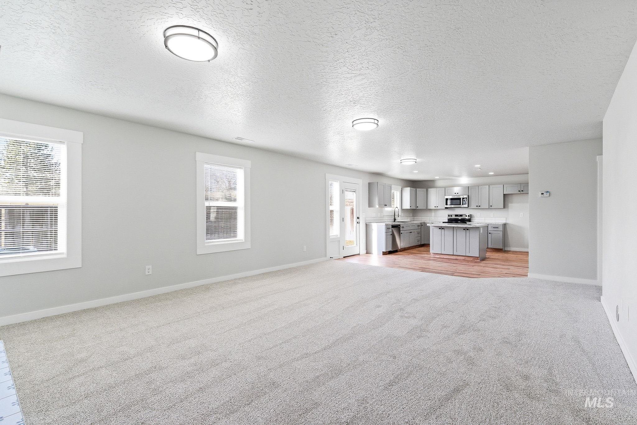 3312 Vistapark Drive Caldwell, ID 83605 - Photo 8 of 17 Unfurnished living room featuring a textured ceiling and light carpet