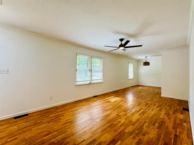 an empty room with wooden floor and windows