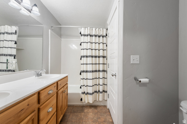 273 West 1010th Street South Logan, UT 84321 - Photo 13 of 19 Bathroom with double vanity, shower / bath combination with curtain, and a textured ceiling