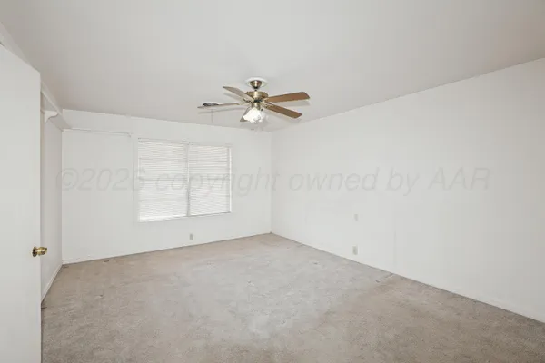 an empty room with chandelier fan and windows