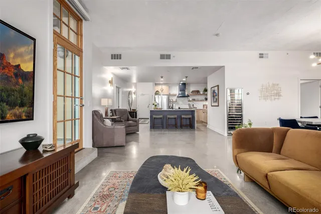 a living room with stainless steel appliances furniture and a kitchen view