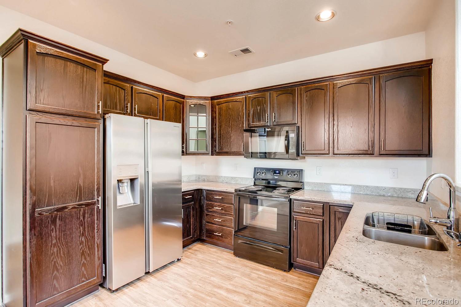 9511 Loggia Street, Unit C Highlands Ranch, CO 80126 - Photo 11 of 32 a kitchen with stainless steel appliances granite countertop a refrigerator stove and sink