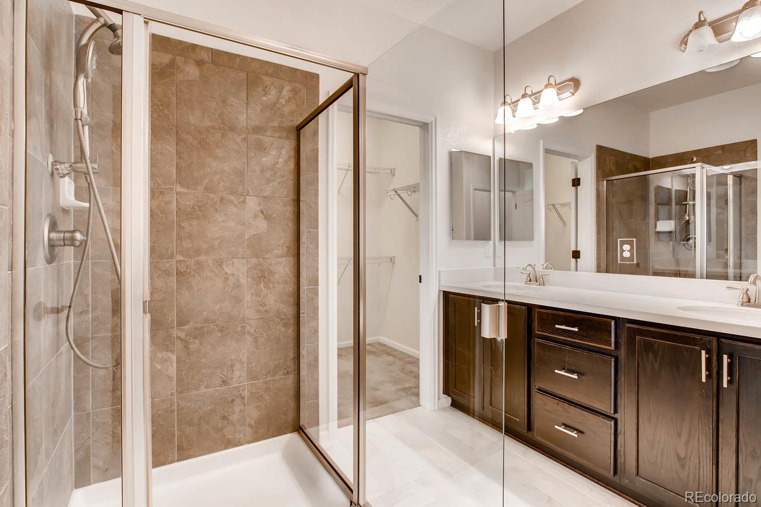 9511 Loggia Street, Unit C Highlands Ranch, CO 80126 - Photo 22 of 32 a bathroom with a double vanity sink a large mirror and shower