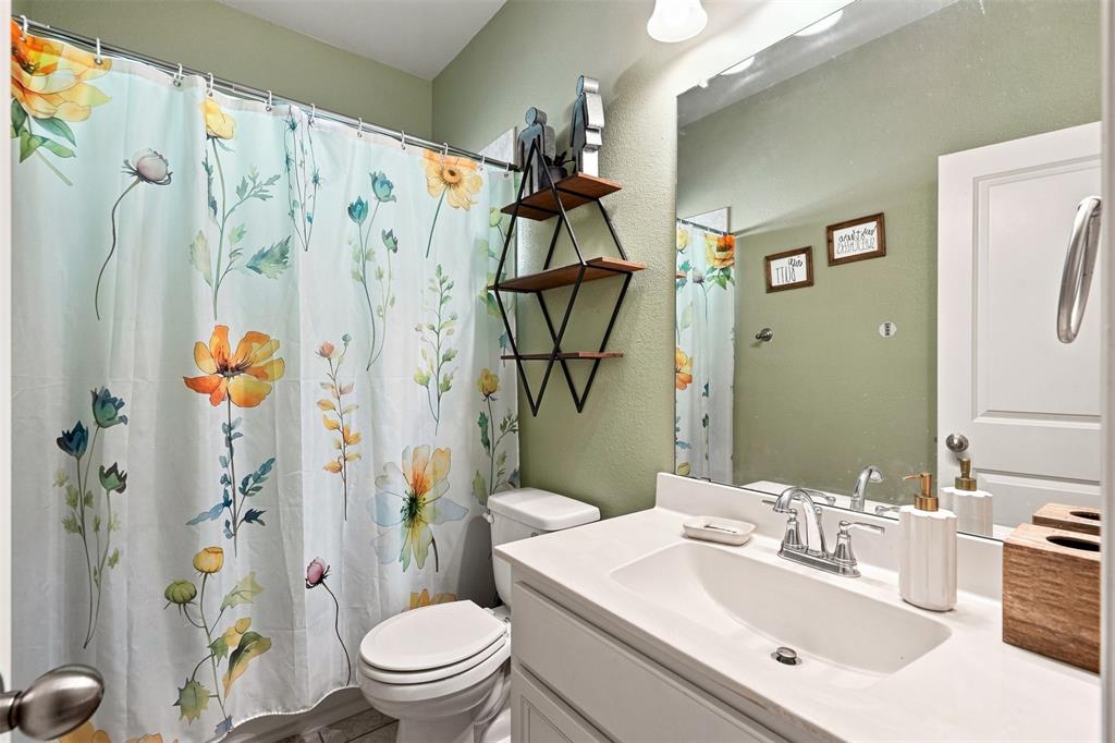 1321 Raleigh Path Denton, TX 76208 - Photo 9 of 35 Bathroom featuring a white vanity with an integrated sink and chrome faucet, a large wall-mounted mirror, and a white toilet
