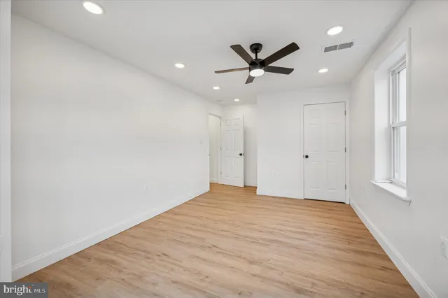 an empty room with wooden floor ceiling fan and windows