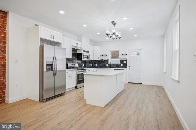 a large kitchen with cabinets wooden floor and stainless steel appliances