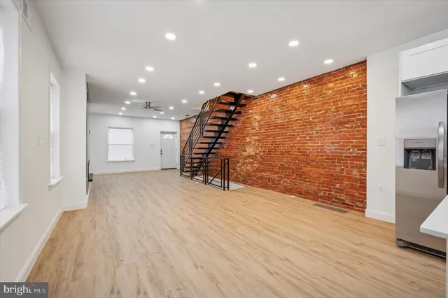a view of an empty room with wooden floor and stairs